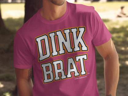 Pink t-shirt with "DINK BRAT" text in white, navy, and yellow lettering.