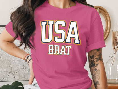 Pink t-shirt with white "USA BRAT" graphic and a small trademark symbol.
