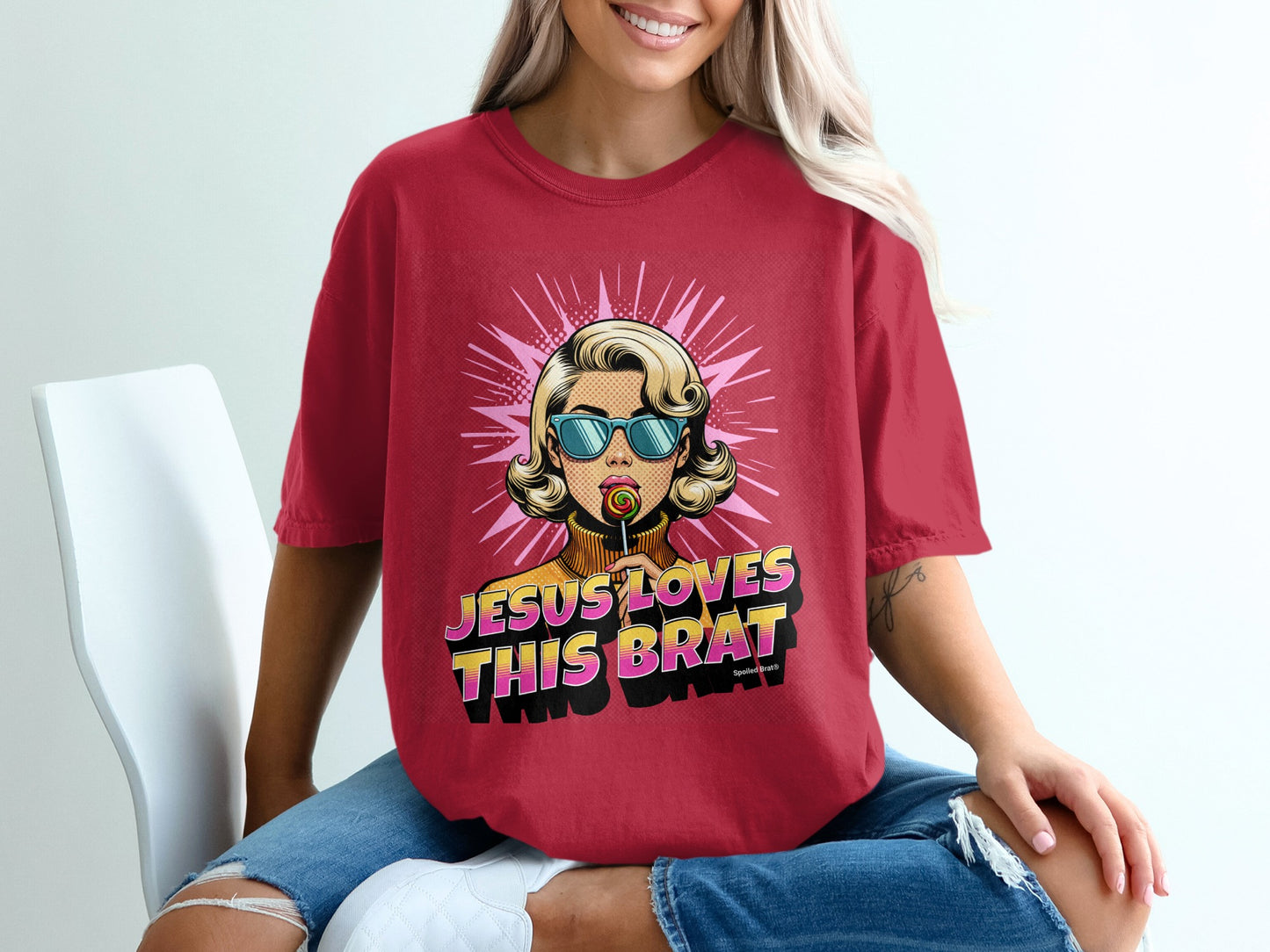 Woman wearing a red t-shirt with "Jesus Loves This Brat" text and lollipop graphic.
