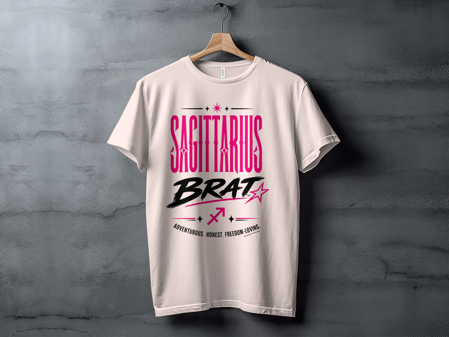 White t-shirt with "SAGITTARIUS BRAT" printed in pink and black text.