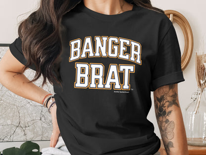 Black t-shirt with "BANGER BRAT" in white and gold collegiate lettering.