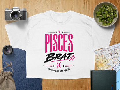 White t-shirt with "PISCES BRAT" in pink and black text.