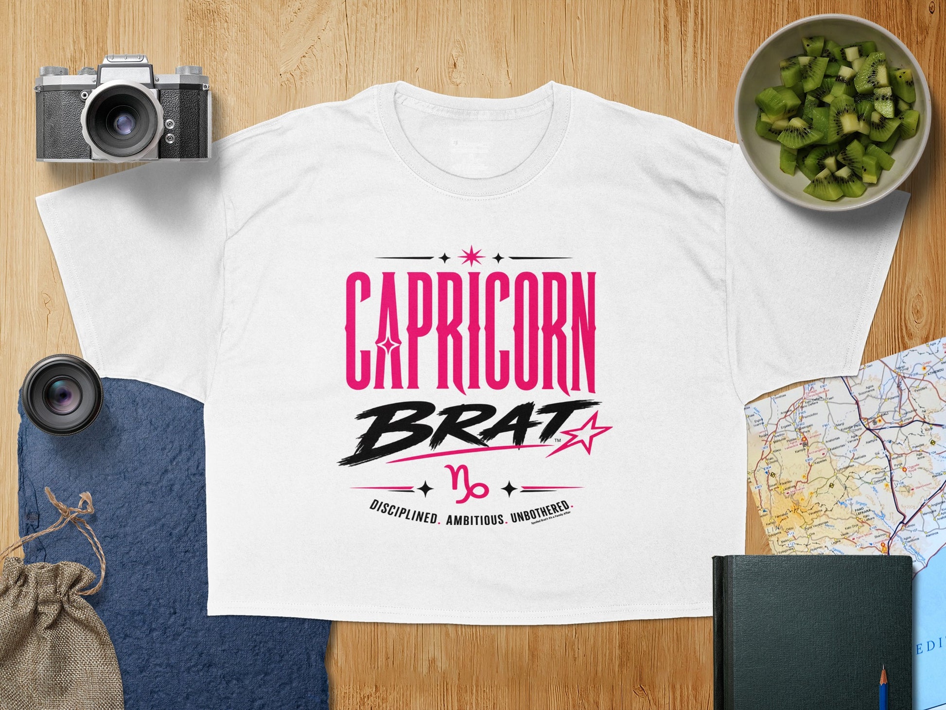 White t-shirt with pink and black "Capricorn Brat" graphic and descriptive text.