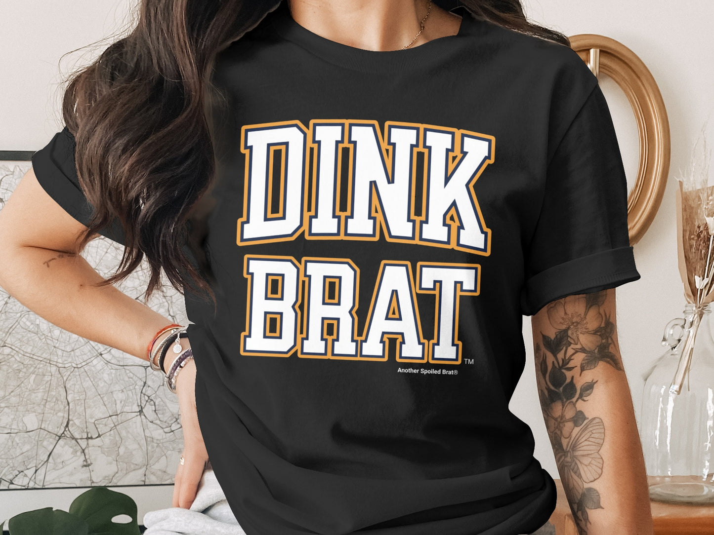Black t-shirt with "DINK BRAT" in collegiate-style font.