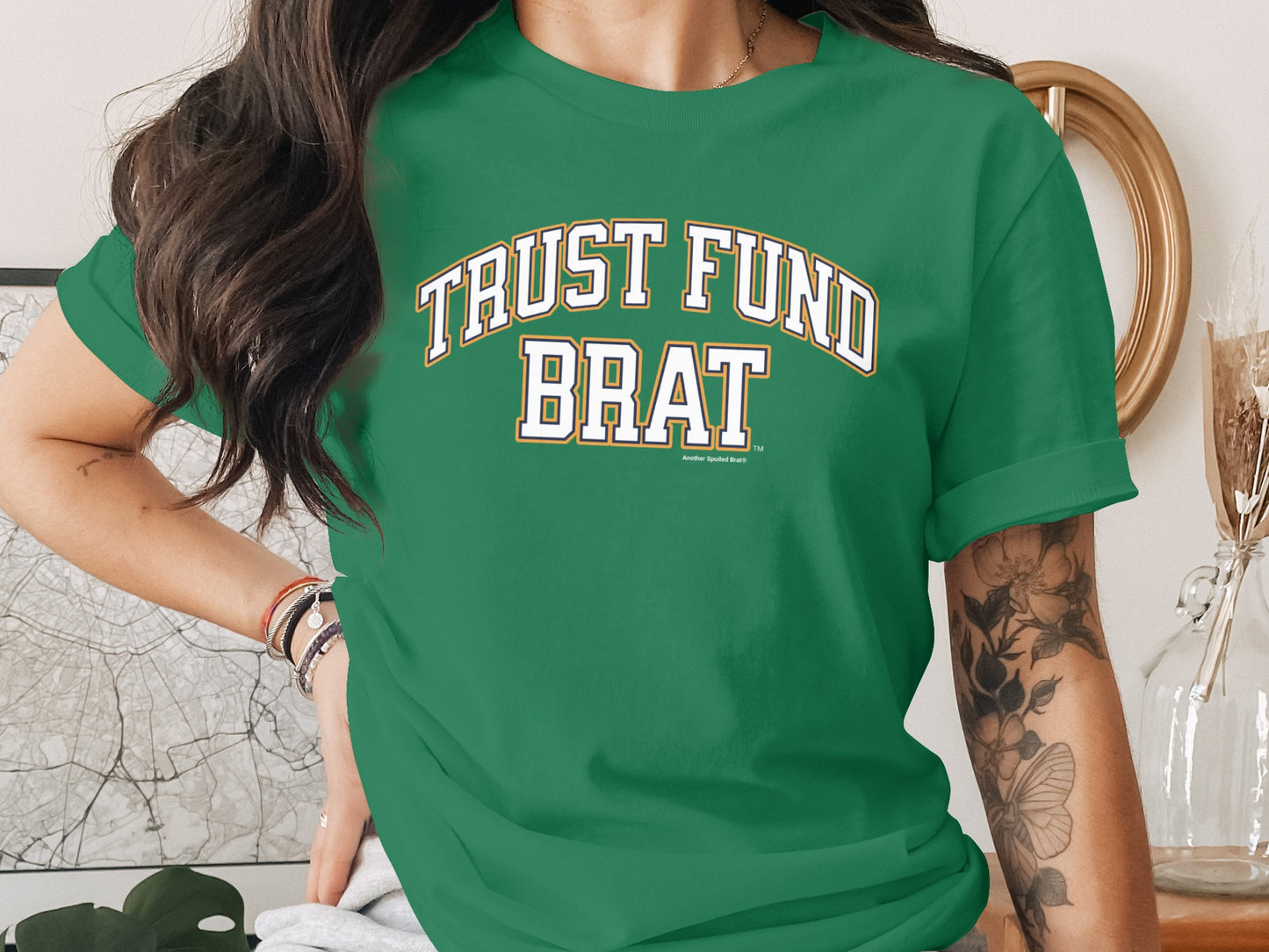 Green t-shirt with "TRUST FUND BRAT" in collegiate font and "Another Spoiled Brat" below.