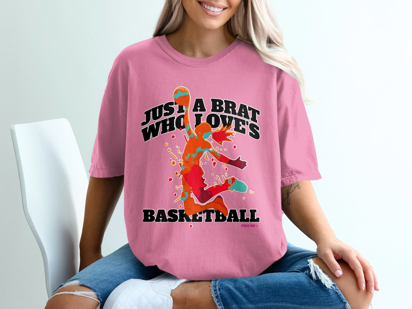 Pink t-shirt with "Just A Brat Who Loves Basketball" graphic.