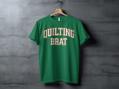 Green t-shirt with "QUILTING BRAT" text in white and gold arching letters.
