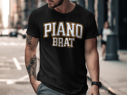 Black t-shirt with "PIANO BRAT" lettering in white and gold.