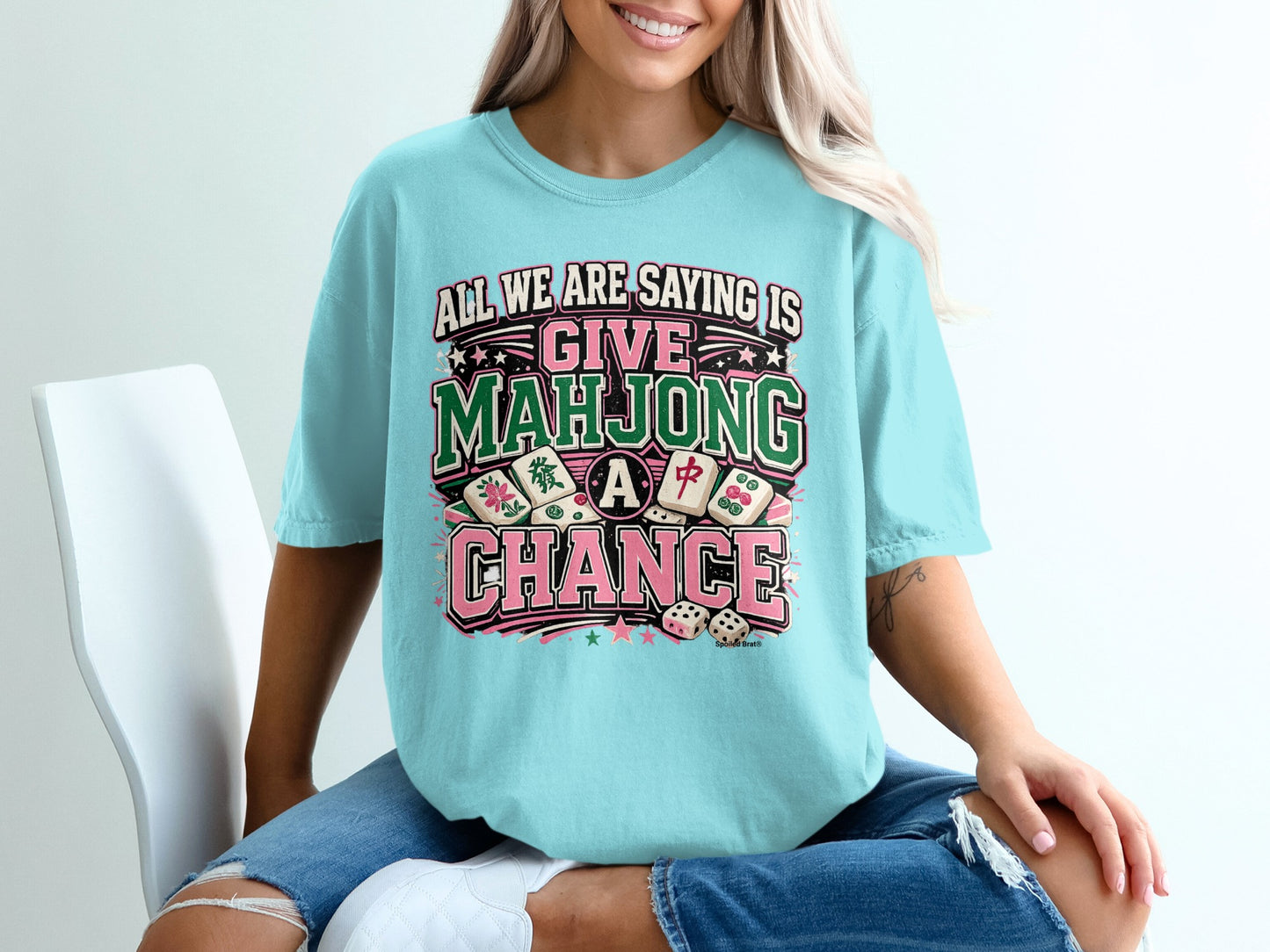 "Mahjong" graphic tee with dice and colorful stars on a light blue t-shirt.