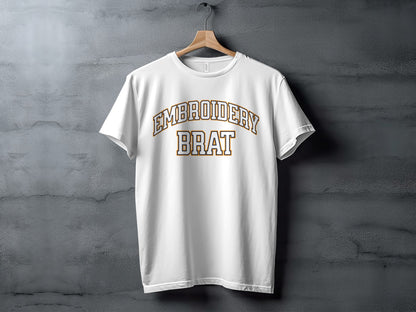 White t-shirt with embroidered "EMBROIDERY BRAT" text in gold and white.