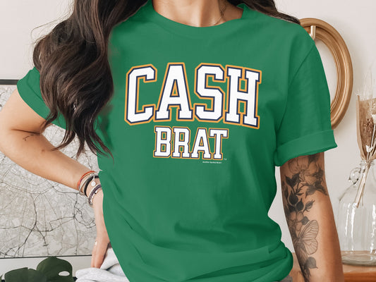 Green t-shirt with white text "CASH BRAT" and "Another Spoiled Brat".