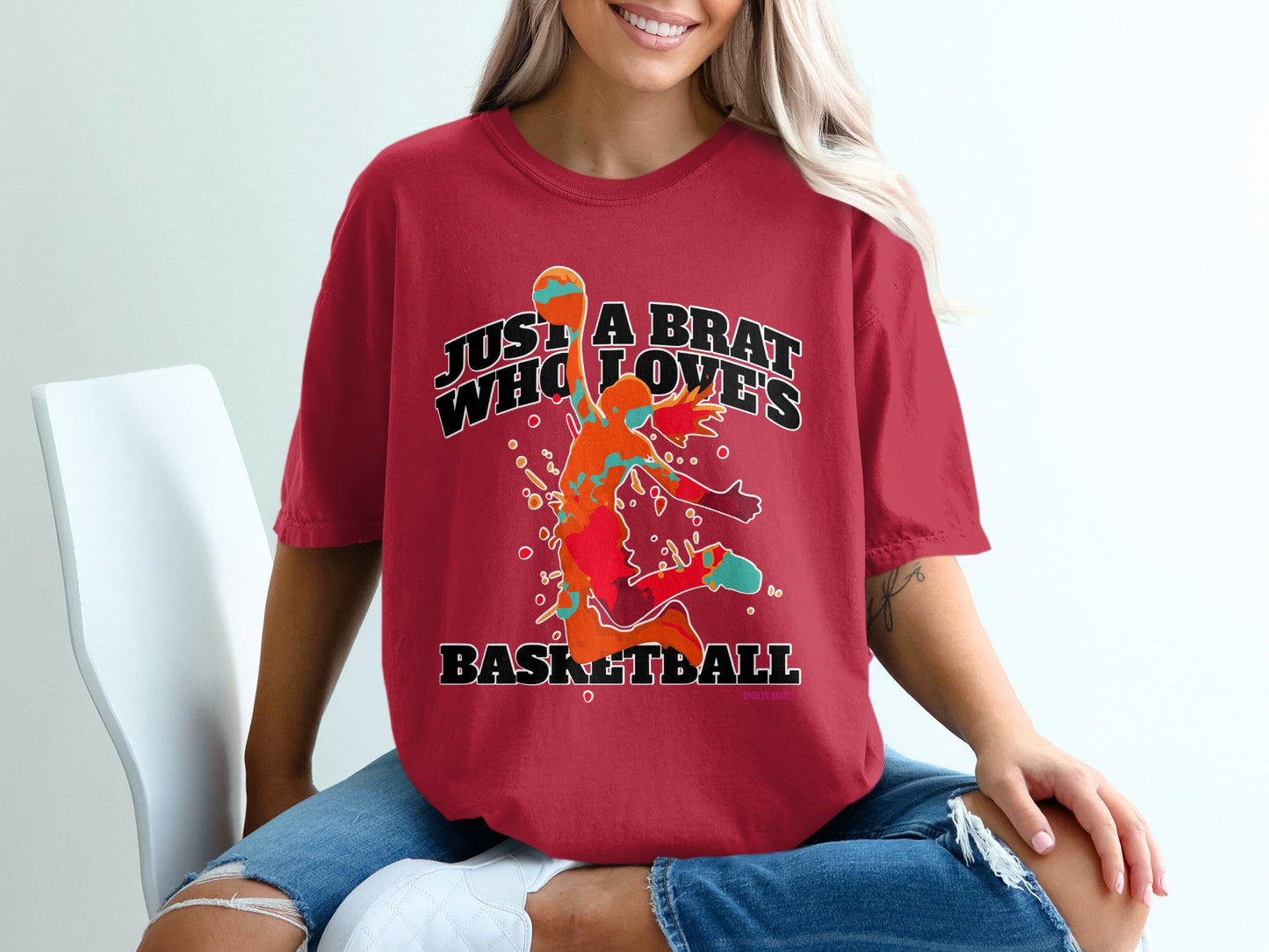 Red t-shirt with "Just a brat who loves basketball" graphic on a woman.