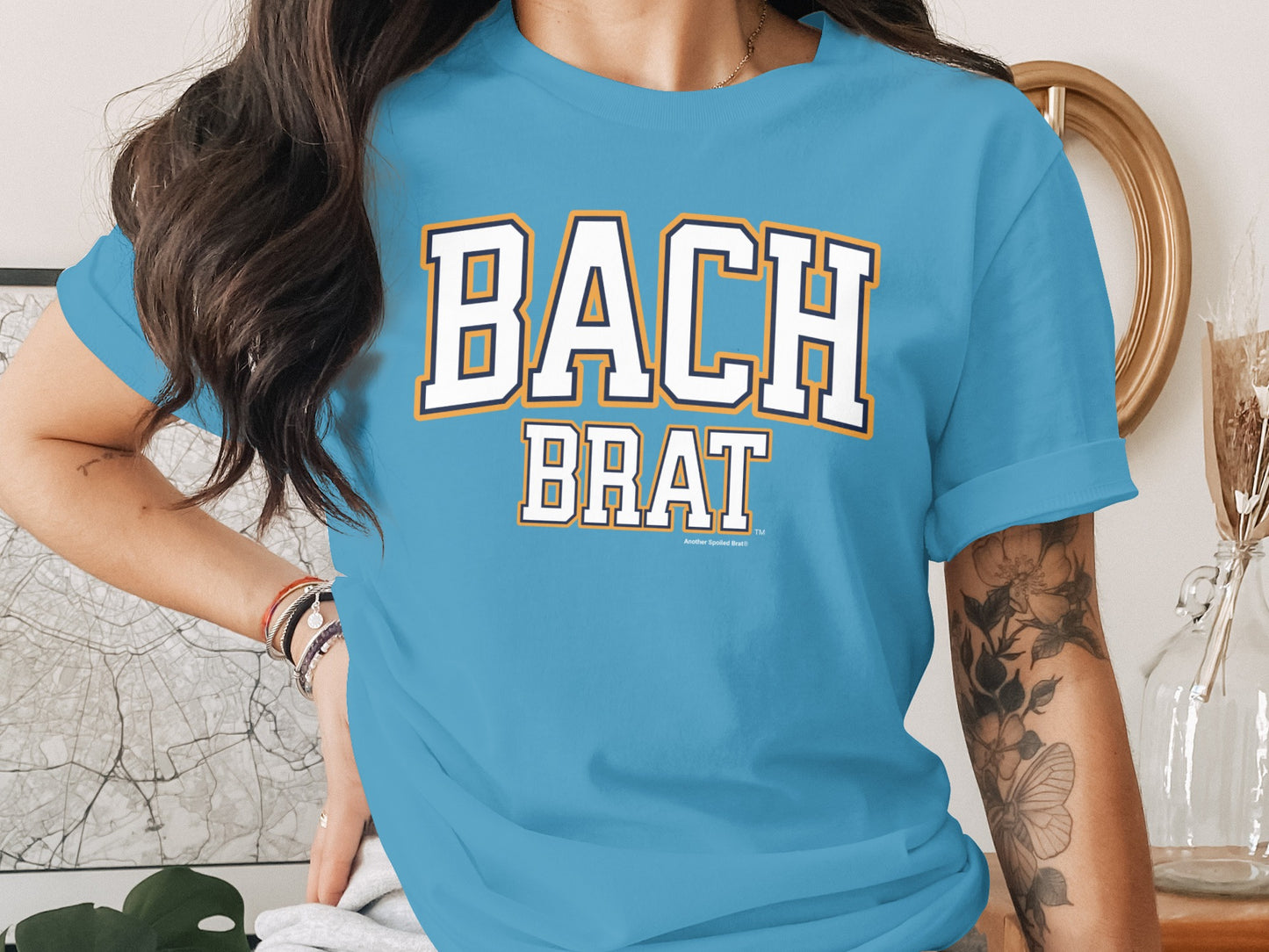 Light blue t-shirt with "BACH BRAT" in white collegiate lettering.