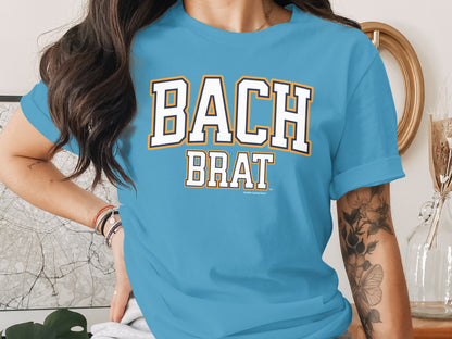 Light blue t-shirt with "BACH BRAT" in white collegiate lettering.