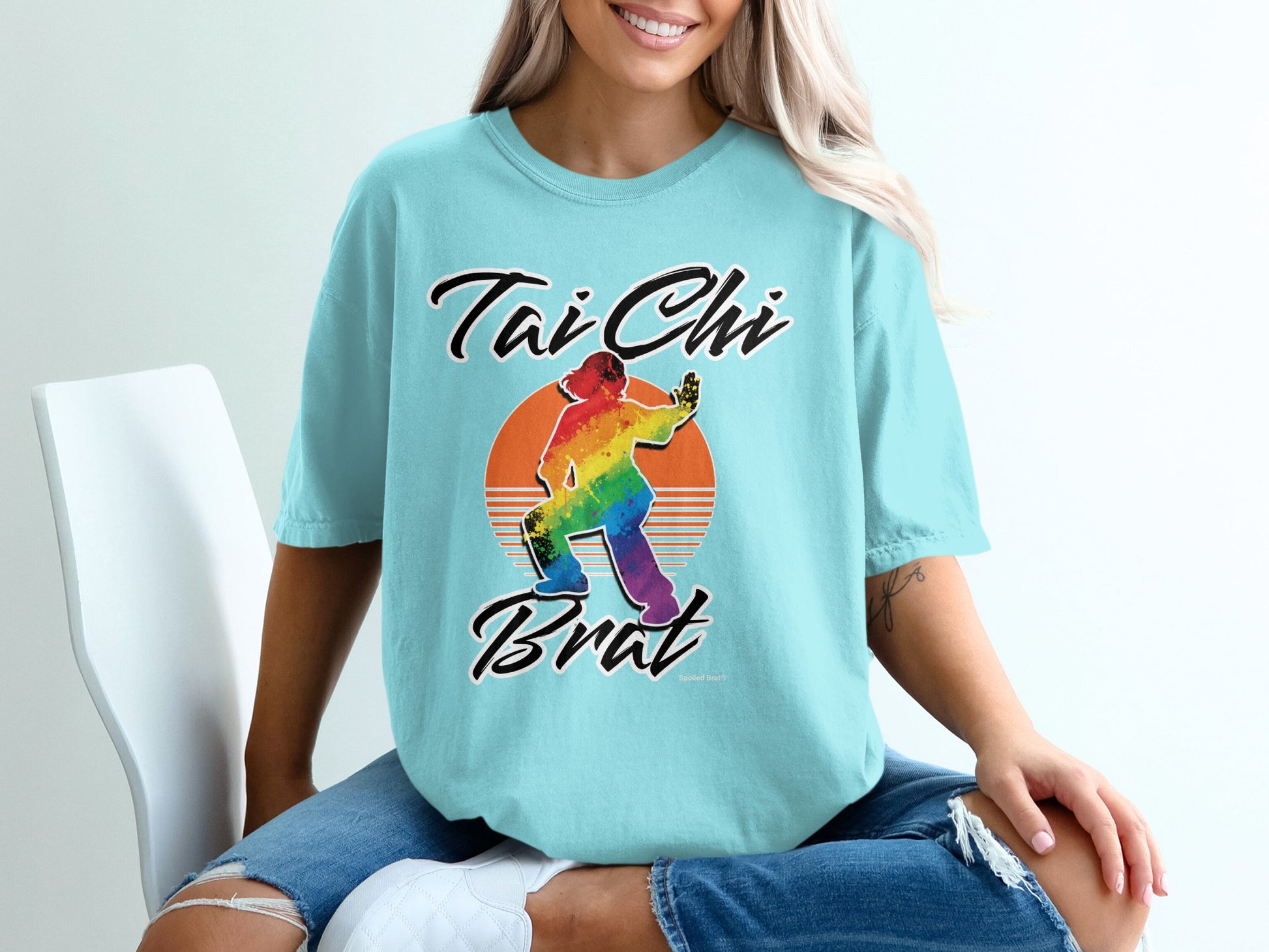Light blue t-shirt with "Tai Chi Brat" and rainbow sunset graphic.