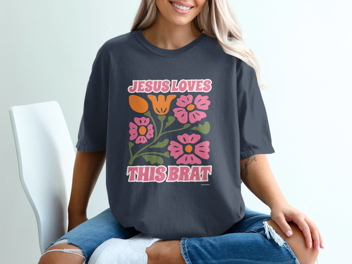 Dark t-shirt with "Jesus Loves This Brat" text and floral design.