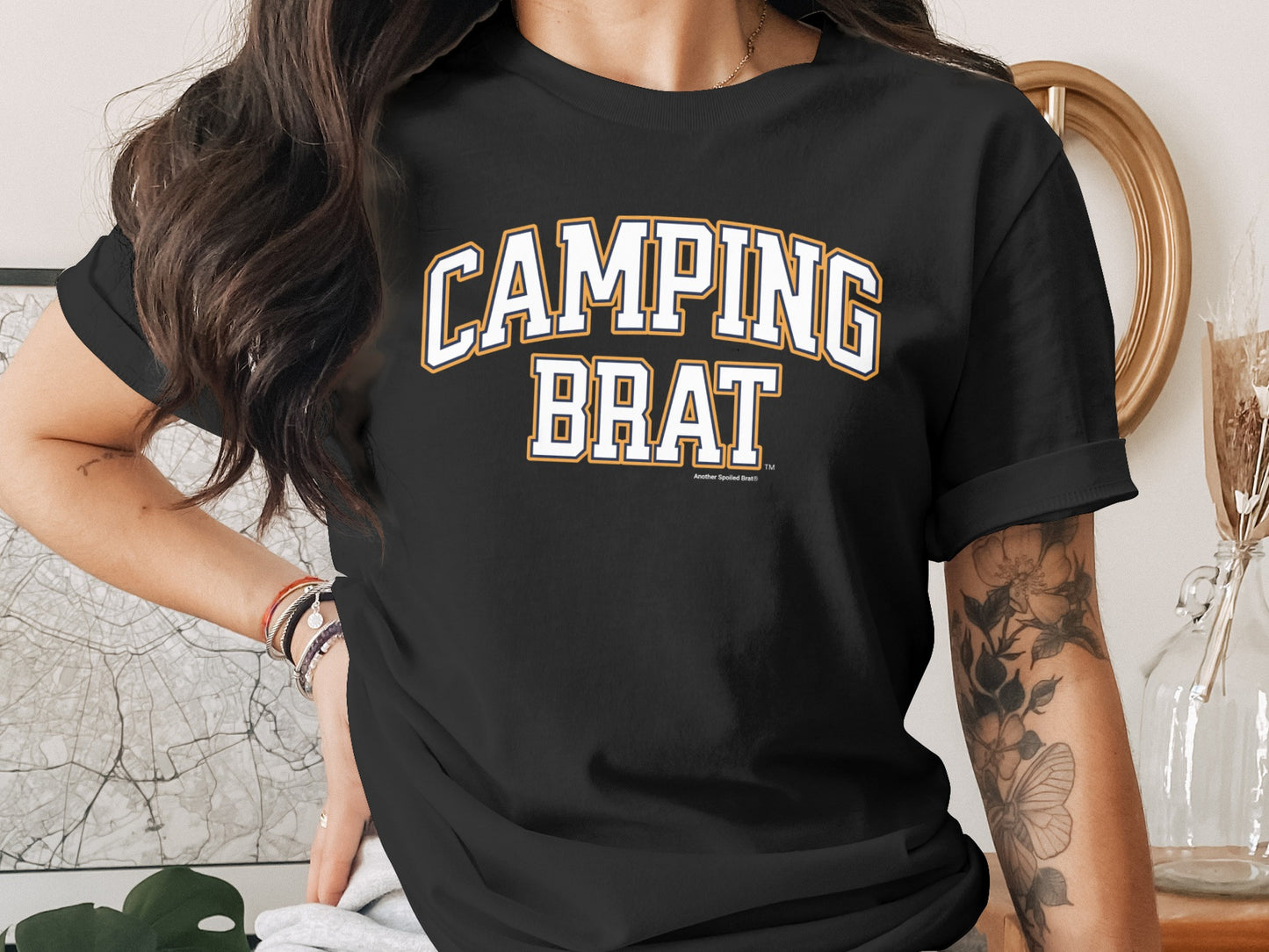 Black t-shirt with white and gold "CAMPING BRAT" text.