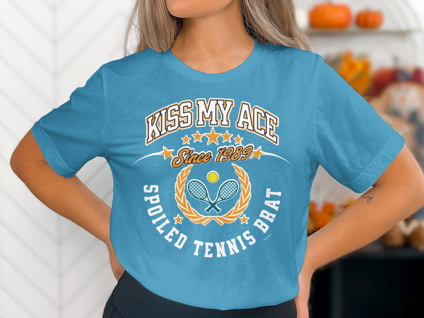 Blue t-shirt with "Kiss My Ace Spoiled Tennis Brat Since 1989" and tennis graphic.