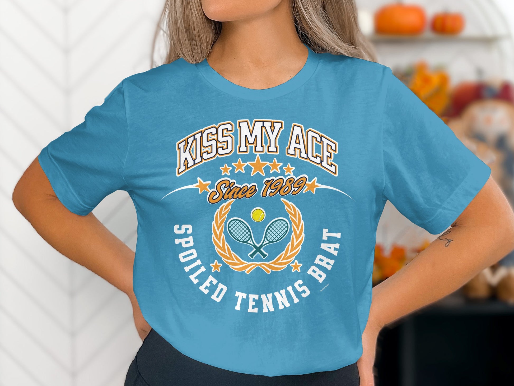 Blue t-shirt with "Kiss My Ace Spoiled Tennis Brat Since 1989" and tennis graphic.