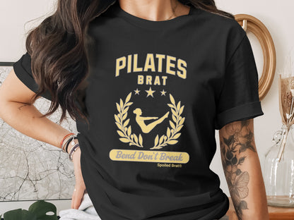 Black t-shirt with "PILATES BRAT" design featuring a laurel wreath and the phrase "Bend Don't Break".