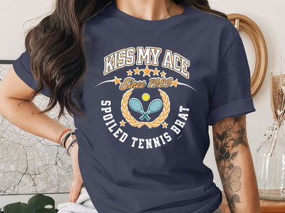 Navy t-shirt with "Kiss My Ace Spoiled Tennis Brat" and tennis racket graphic.