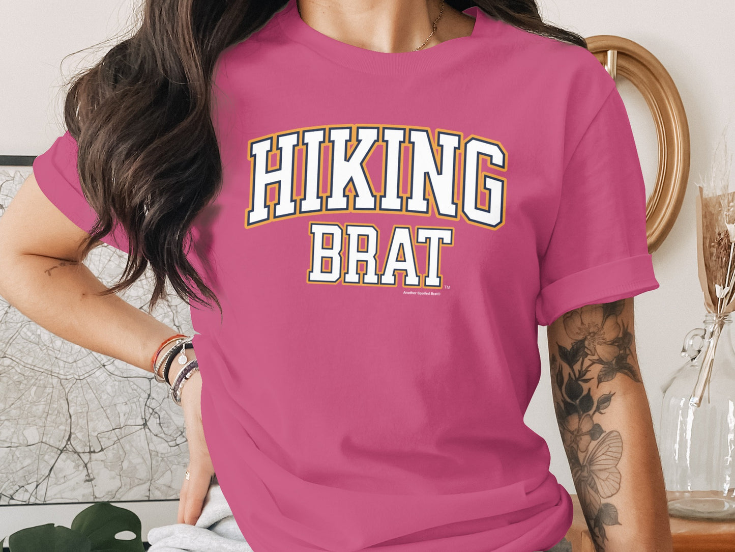 Pink t-shirt with "HIKING BRAT" text in collegiate style lettering.