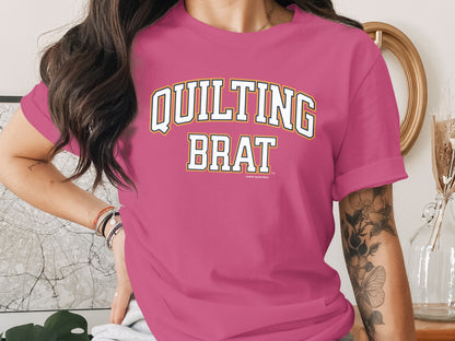 Pink t-shirt with "QUILTING BRAT" text in collegiate style lettering.