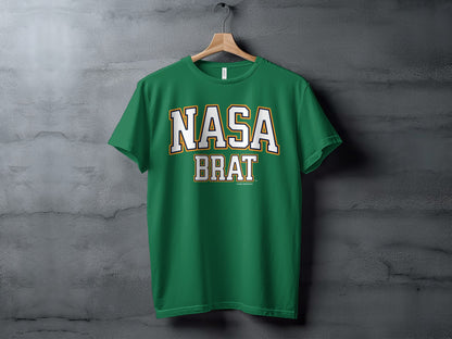 Green t-shirt with white and gold "NASA BRAT" text hanging on a wooden hanger.