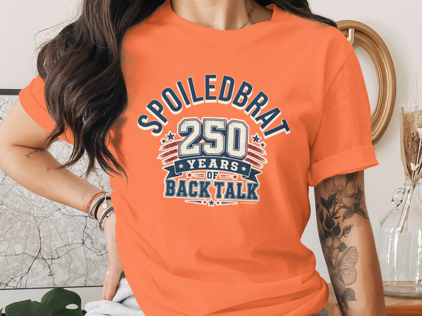 Orange t-shirt with "SPOILED BRAT 250 YEARS OF BACK TALK" graphic.