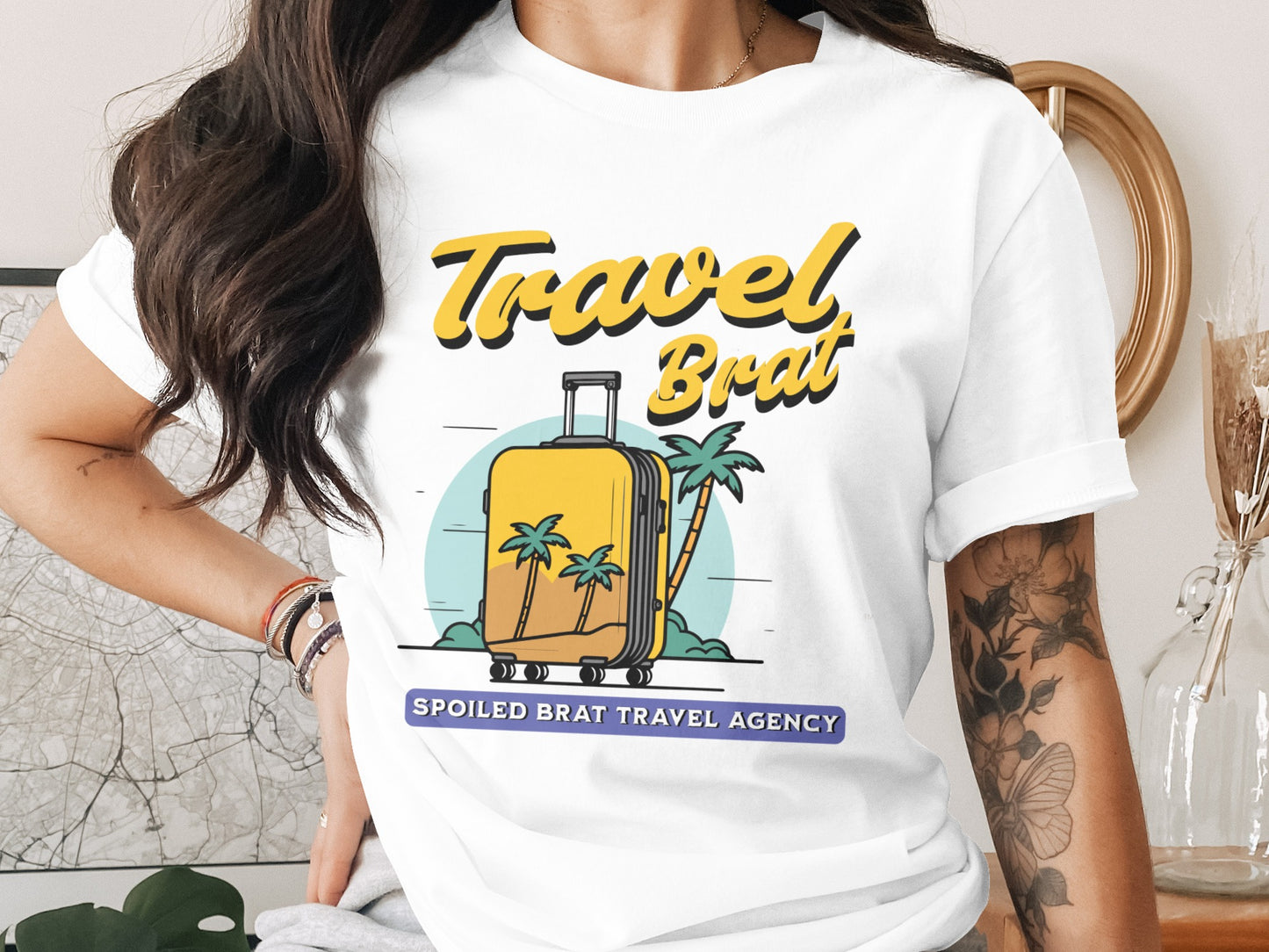 White t-shirt with yellow text "Travel Brat" and a yellow suitcase graphic.