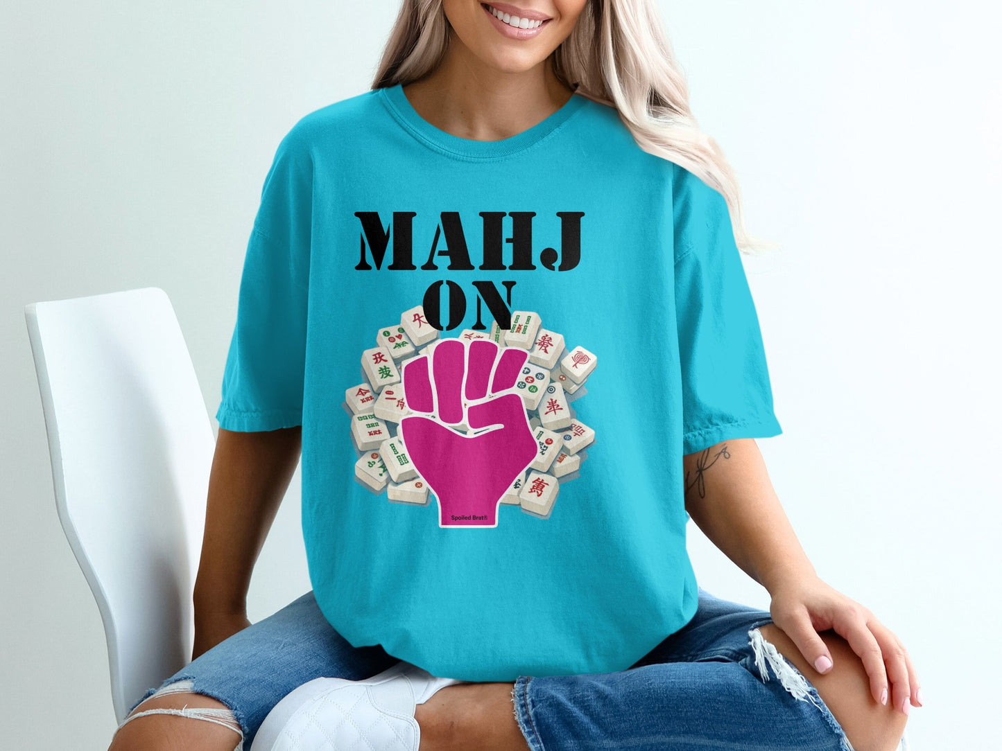 Turquoise t-shirt with "MAHJ ON" and pink fist Mahjong tile graphic.