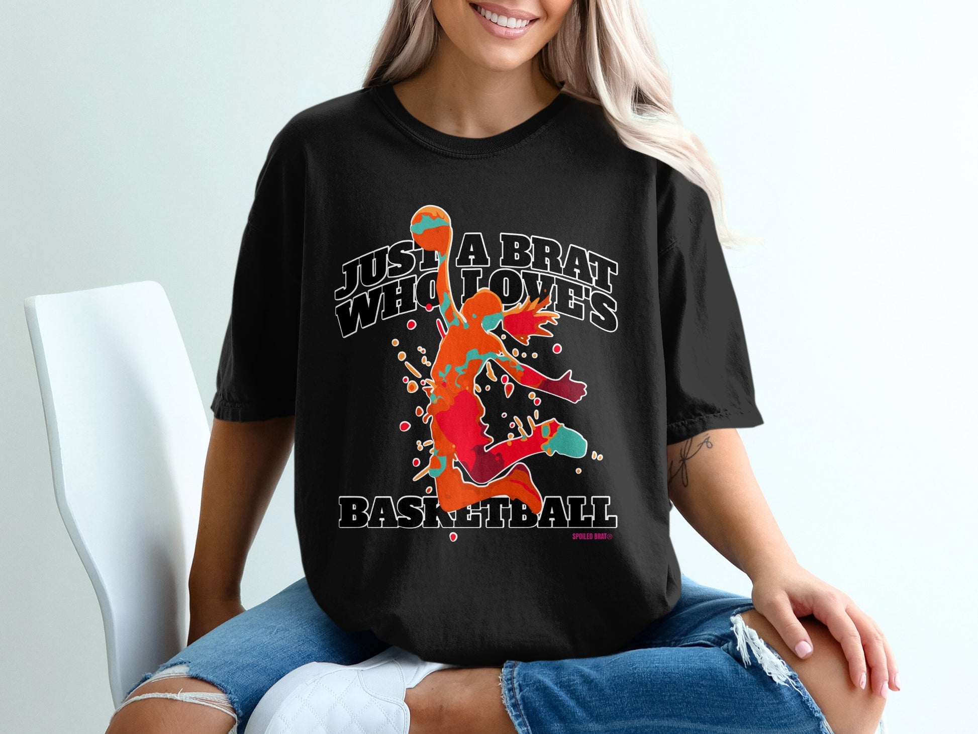 Black t-shirt with colorful basketball player graphic and text "JUST A BRAT WHO LOVES BASKETBALL".
