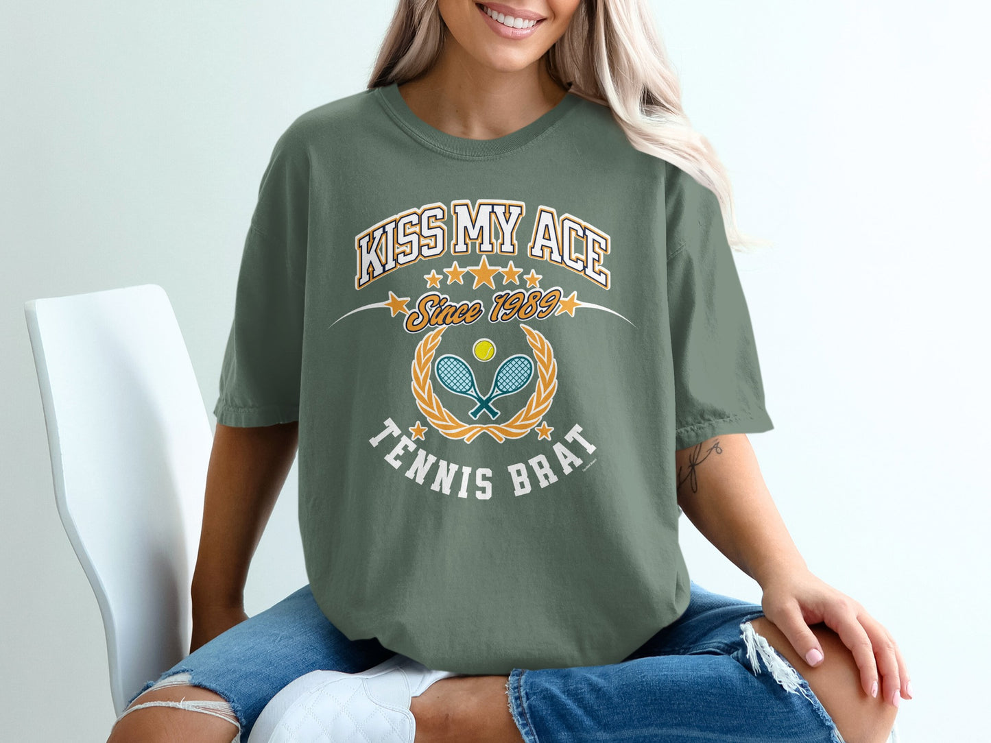 Green t-shirt with "Kiss My Ace Since 1989 Tennis Brat" text and tennis graphic.