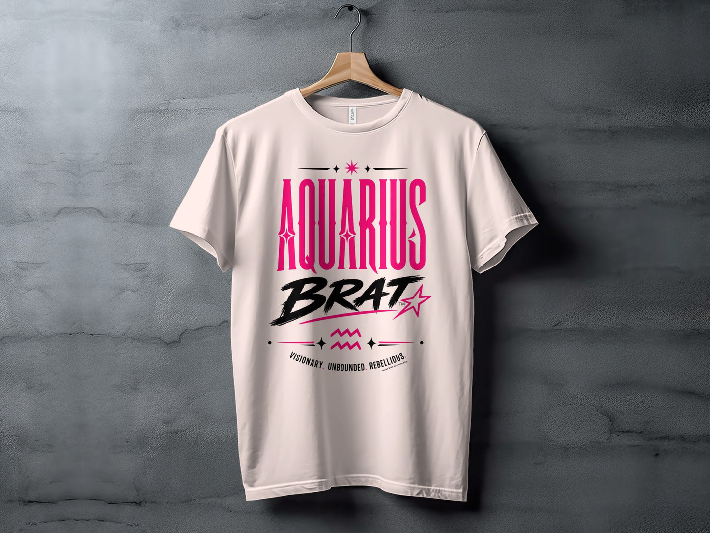 Pink text on a white t-shirt reads "AQUARIUS BRAT" with symbols below.