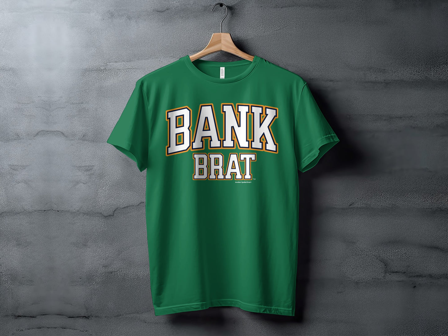 Green t-shirt with white and gold "BANK BRAT" text against a concrete background.