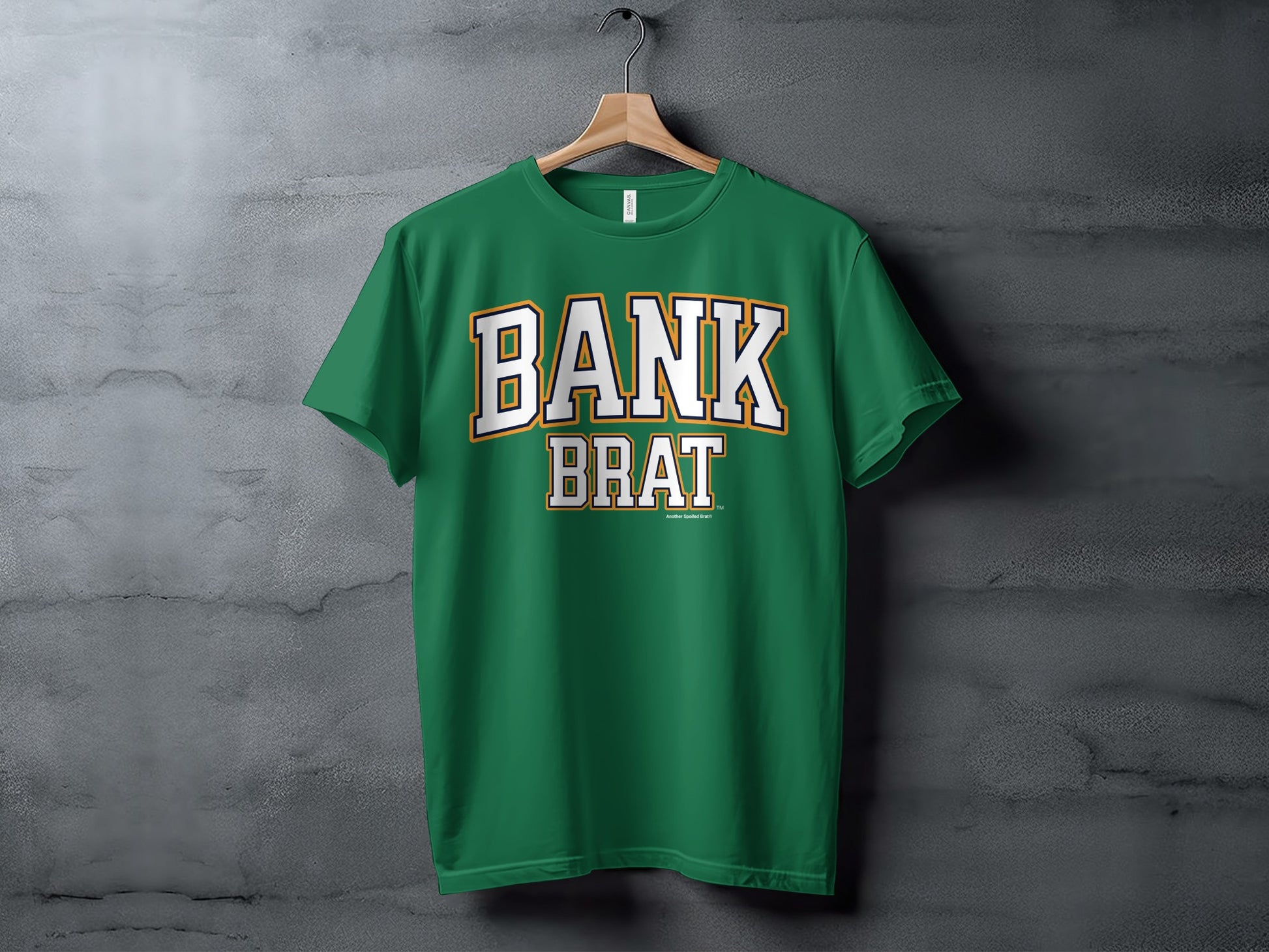 Green t-shirt with white and gold "BANK BRAT" text against a concrete background.