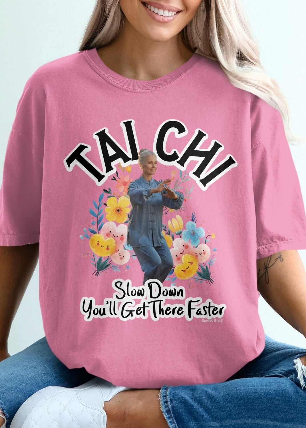Pink t-shirt with "Tai Chi" text and woman practicing Tai Chi amidst flowers.