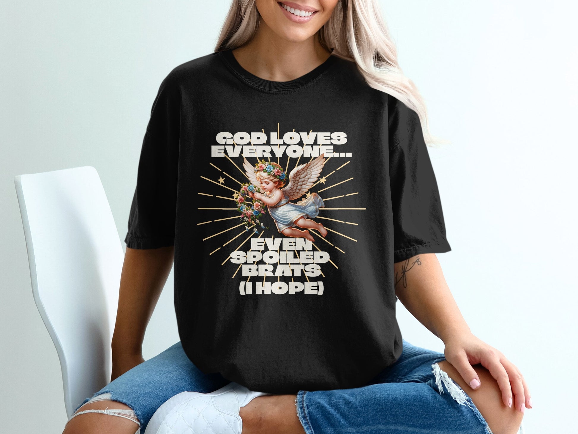 Black t-shirt with angel graphic and text "God loves everyone... even spoiled brats (I hope)".