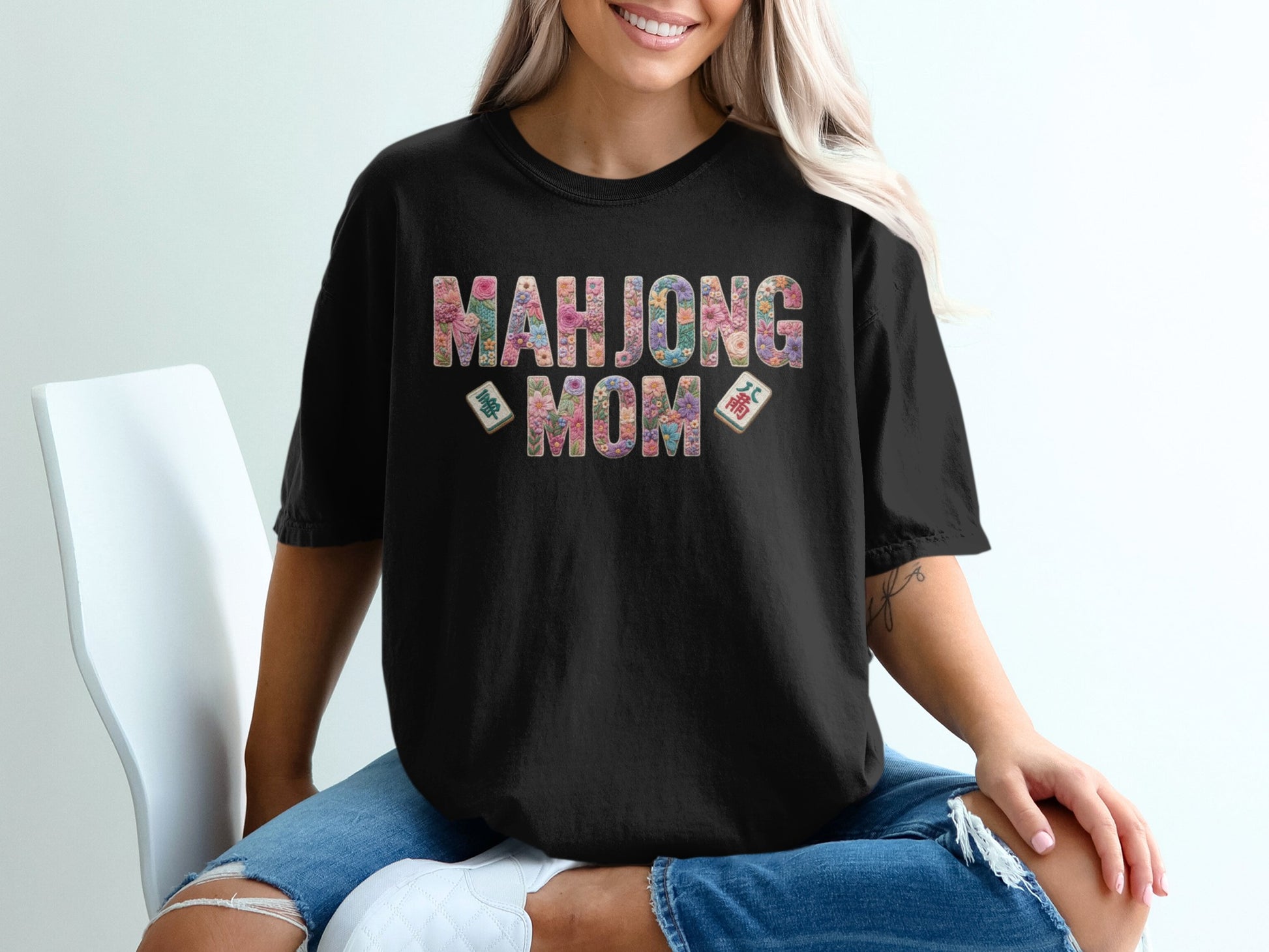 Black t-shirt with "MAHJONG MOM" in colorful floral letters and mahjong tiles.