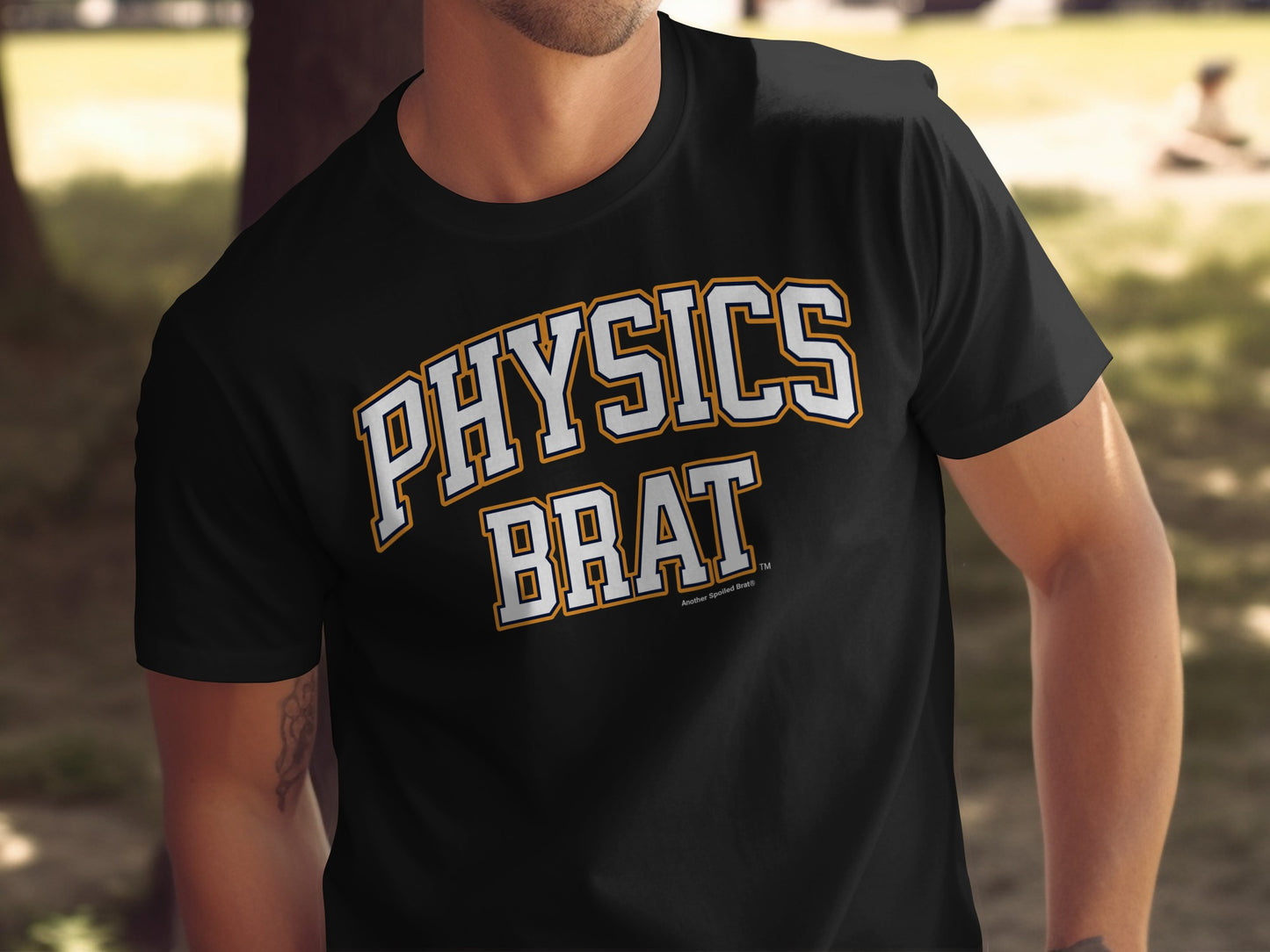 A person wearing a black t-shirt with the words Physics Brat printed in white and gold collegiate letters.