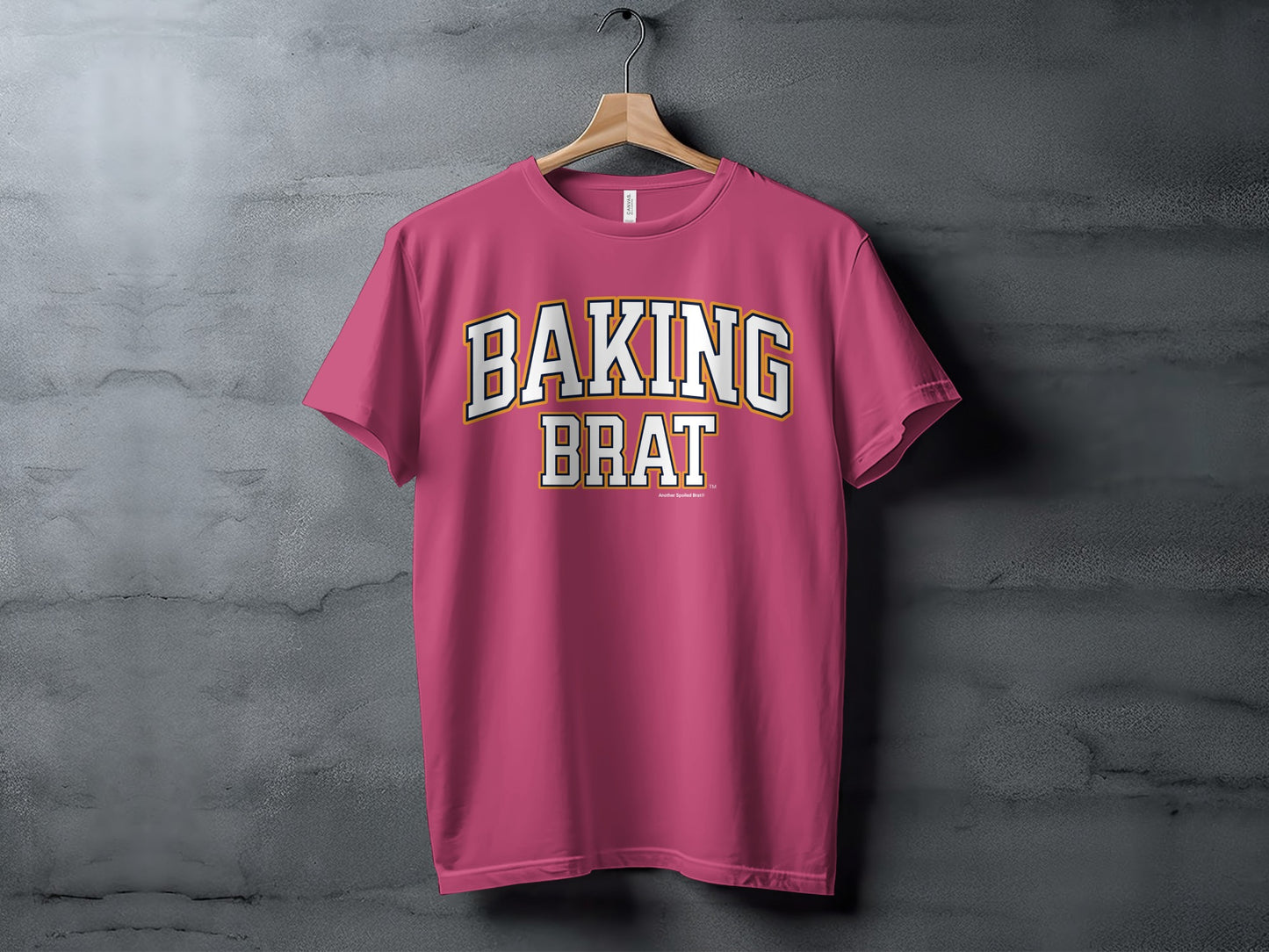 Pink t-shirt with "BAKING BRAT" text in white and yellow collegiate font.