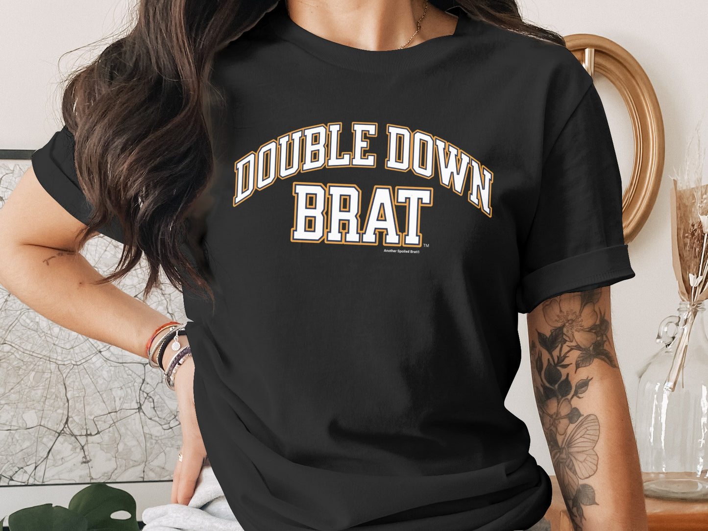 Black t-shirt with "DOUBLE DOWN BRAT" text in white and gold varsity-style letters.