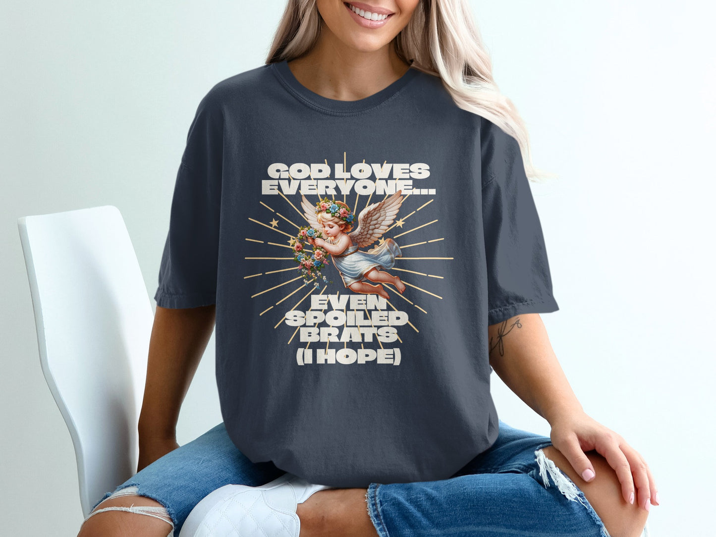 Dark t-shirt with angel, flowers, and text "GOD LOVES EVERYONE... EVEN SPOILED BRATS (I HOPE)".