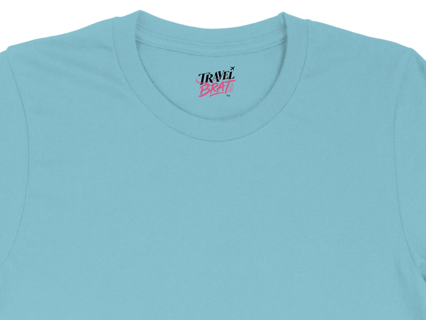 Blue t-shirt with "Travel Brat" logo and airplane graphic on collar label.