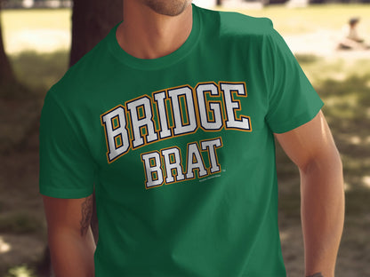 Green t-shirt with "BRIDGE BRAT" text in white and yellow athletic font.
