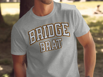 Grey t-shirt with arched "BRIDGE" above "BRAT" text in white and orange.