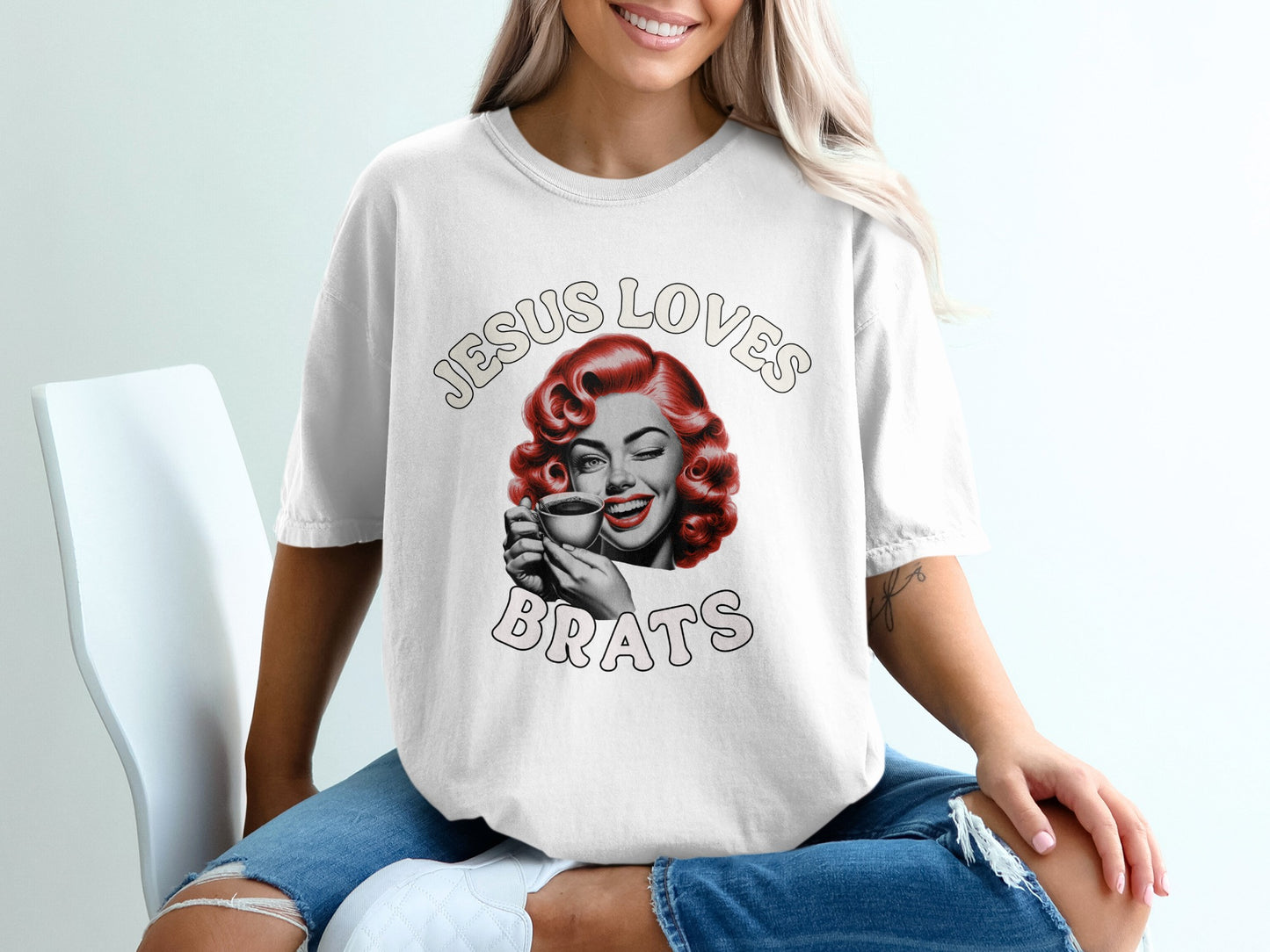 White t-shirt with "Jesus Loves Brats" and retro woman winking with coffee.