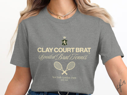 Grey t-shirt with "CLAY COURT BRAT" and tennis rackets.
