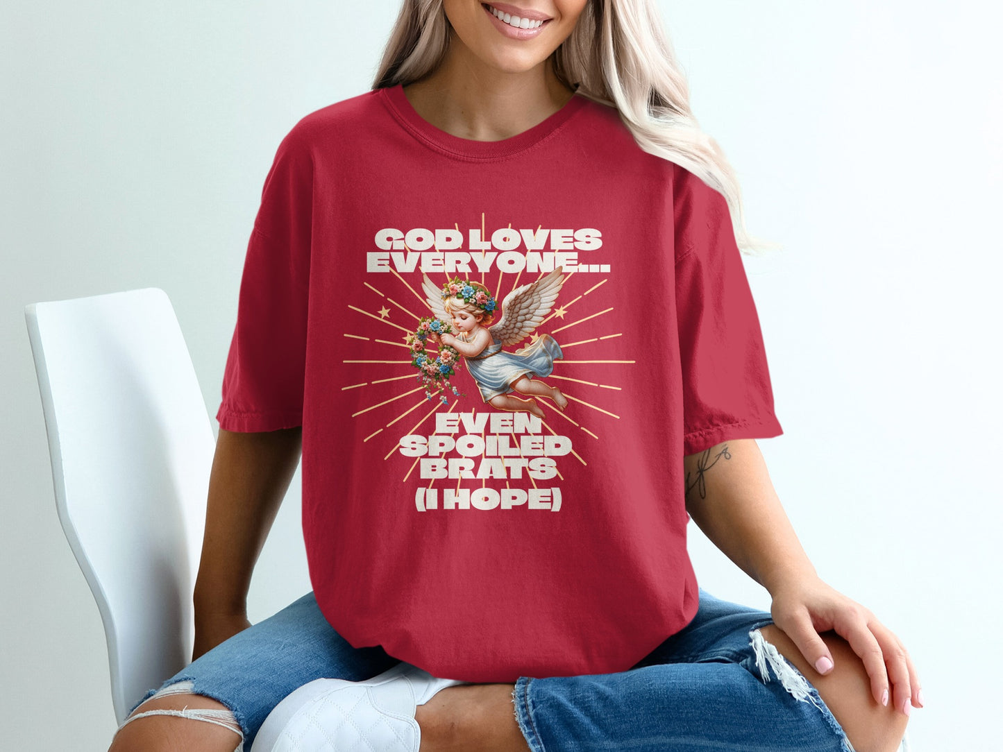 Red t-shirt with "GOD LOVES EVERYONE... EVEN SPOILED BRATS (I HOPE)" text and angel graphic.