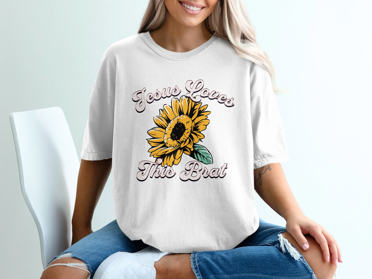 White t-shirt with "Jesus Loves This Brat" and a sunflower graphic.